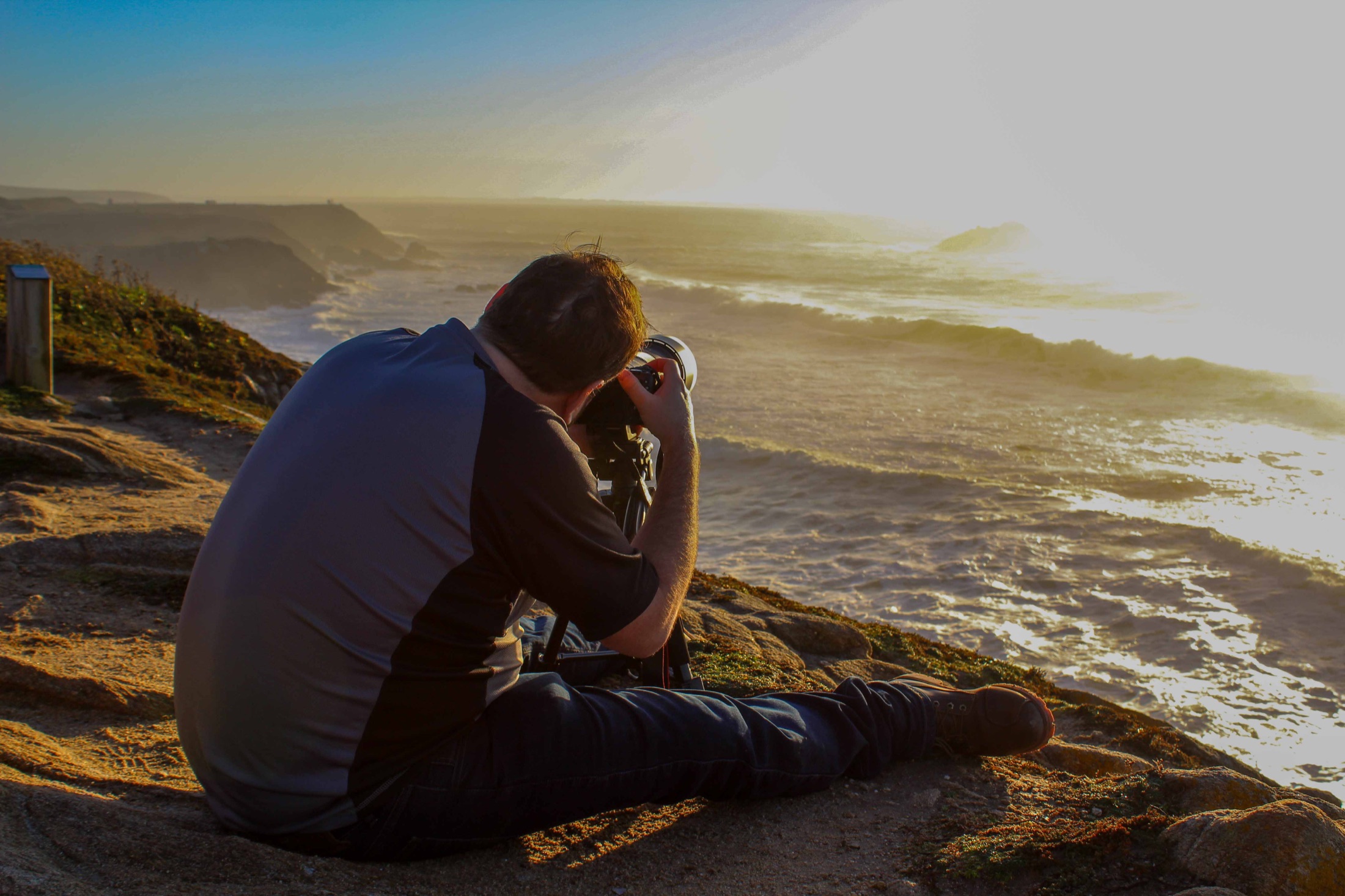 Photographe face à l’océan au coucher du soleil